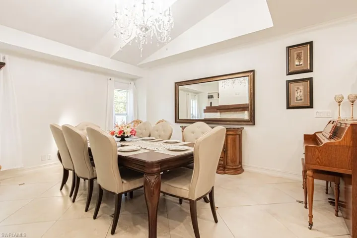 Dining area with a chandelier, vaulted ceiling, and light tile patterned flooring