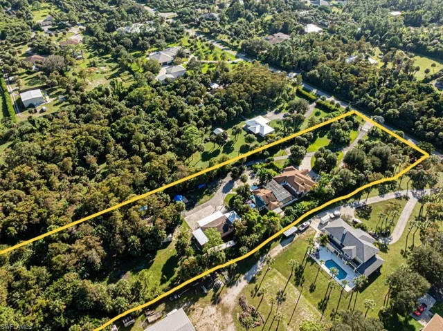 Aerial perspective of suburban area with property parcel outlined and a tree filled landscape