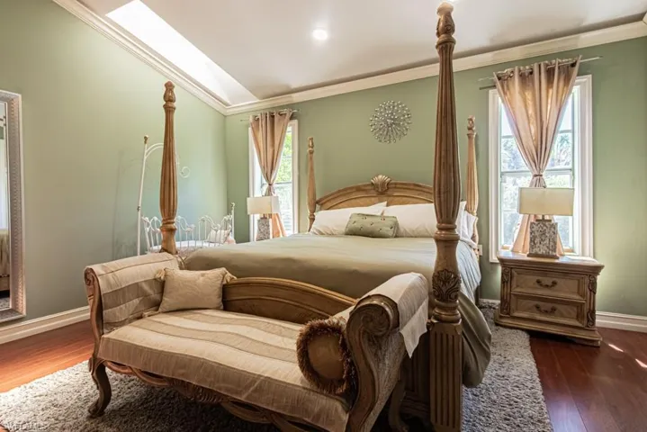 Bedroom featuring dark wood-type flooring, crown molding, a skylight, and lofted ceiling