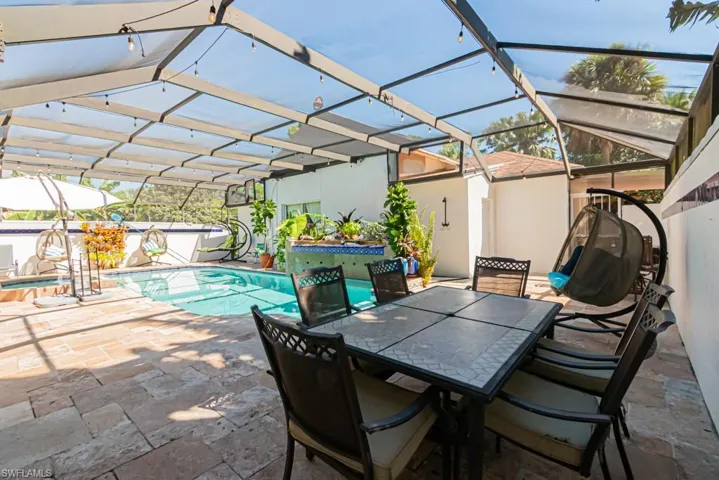 View of patio with glass enclosure, an outdoor pool, a sunroom, and outdoor dining space