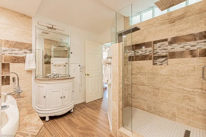Full bathroom featuring vanity, a stall shower, wood finished floors, and tile walls