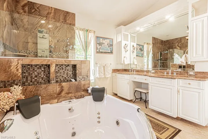 Bathroom featuring double vanity, a stall shower, and a whirlpool tub