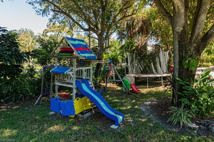 View of play area with a trampoline and a lawn