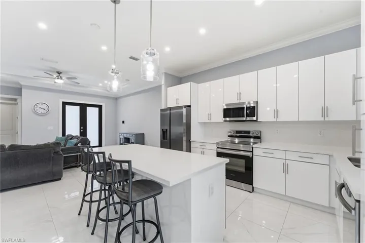 Kitchen featuring hanging light fixtures, stainless steel appliances, a center island, a breakfast bar, and white cabinetry