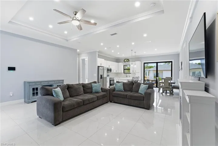 Living area featuring ceiling fan, ornamental molding, recessed lighting, and a raised ceiling