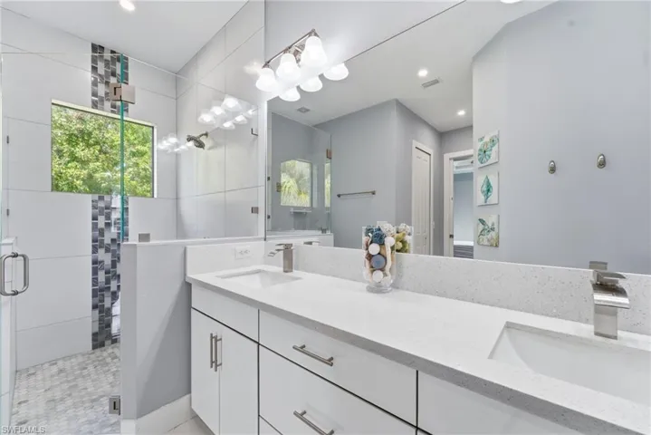 Full bathroom featuring a stall shower, double vanity, and recessed lighting