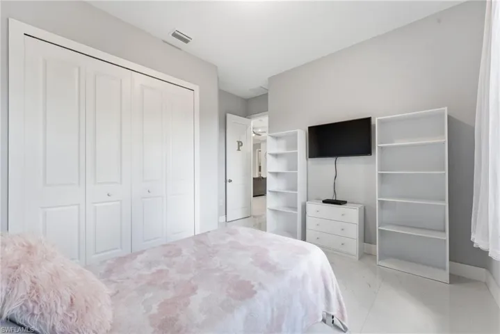 Bedroom featuring light marble finish flooring and a closet