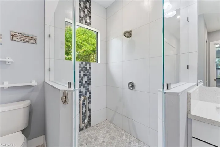 Bathroom featuring tiled shower and vanity