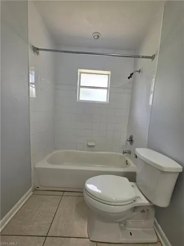 White tile shower surround with a built-in tub, frosted window, and recessed lighting