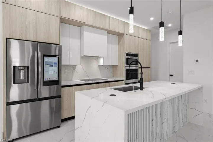 Kitchen with appliances with stainless steel finishes, light marble finish floors, a sink, modern cabinets, and recessed lighting