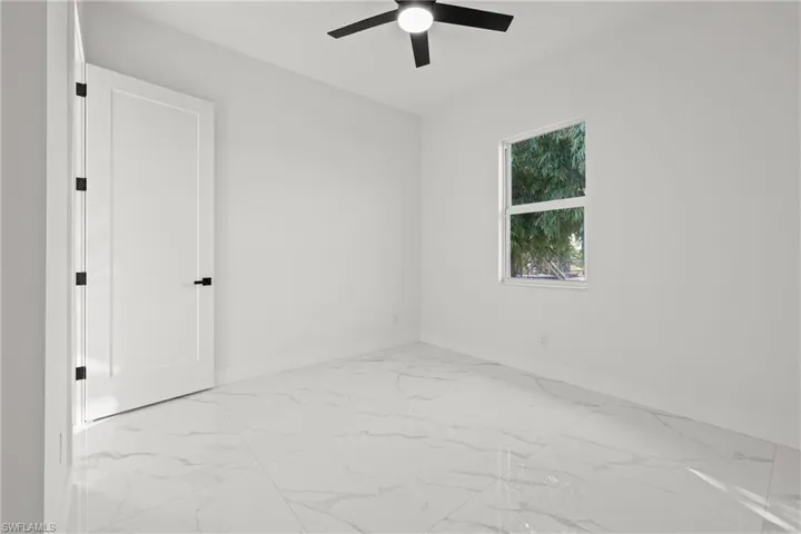 Unfurnished room featuring baseboards, a ceiling fan, and marble finish floors