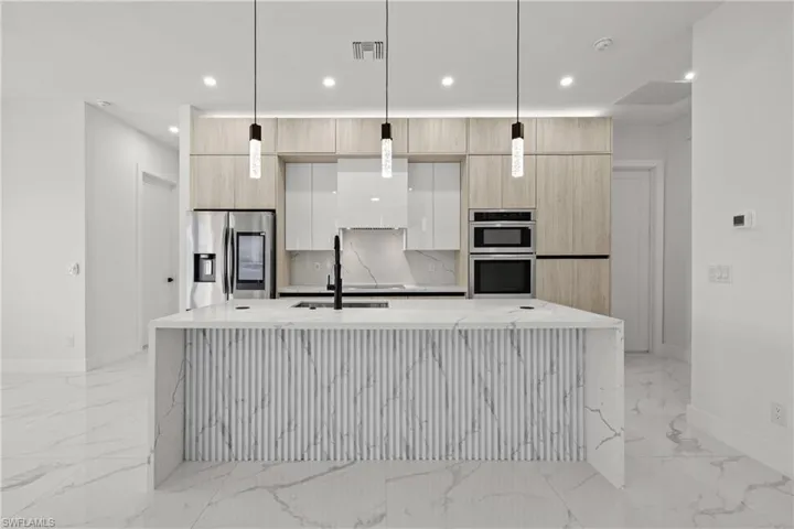 Kitchen with appliances with stainless steel finishes, modern cabinets, light marble finish flooring, a sink, and recessed lighting
