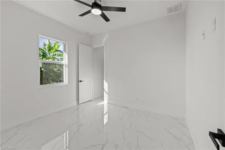 Empty room with baseboards, a ceiling fan, and marble look tile flooring