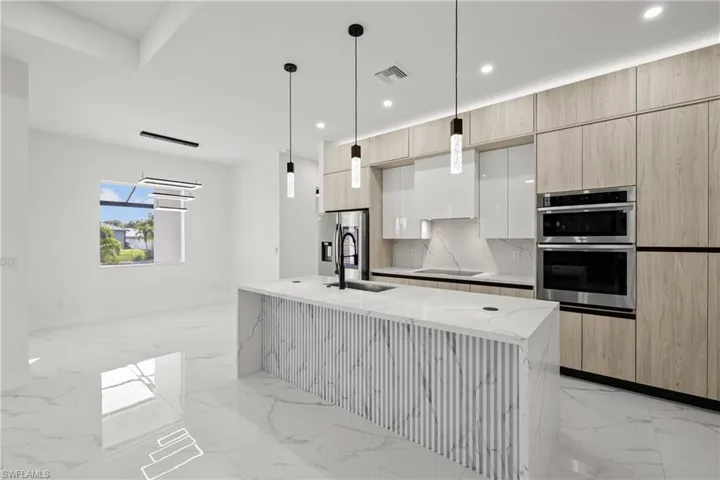 Kitchen with light marble finish flooring, modern cabinets, appliances with stainless steel finishes, recessed lighting, and light stone countertops