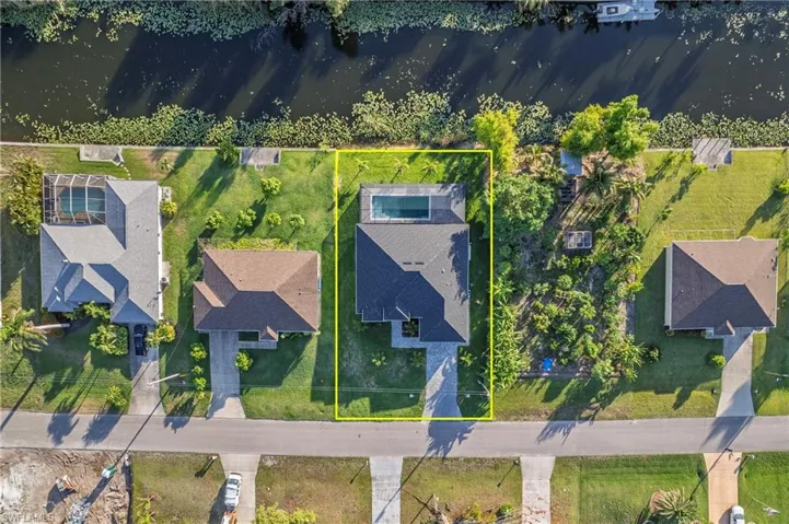 Aerial perspective of suburban area with property parcel outlined and a large body of water