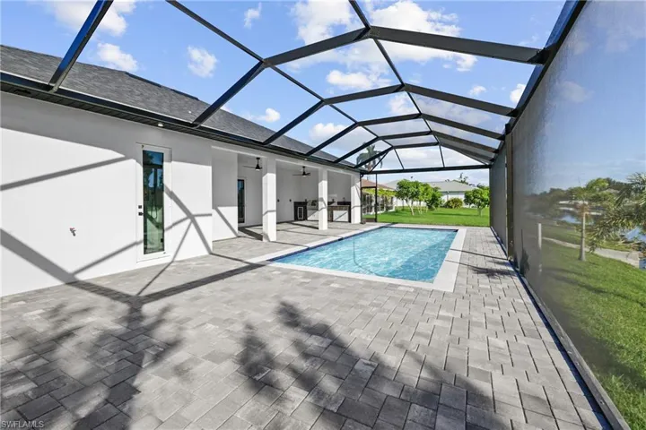 Outdoor pool featuring a patio, ceiling fan, a lawn, and glass enclosure