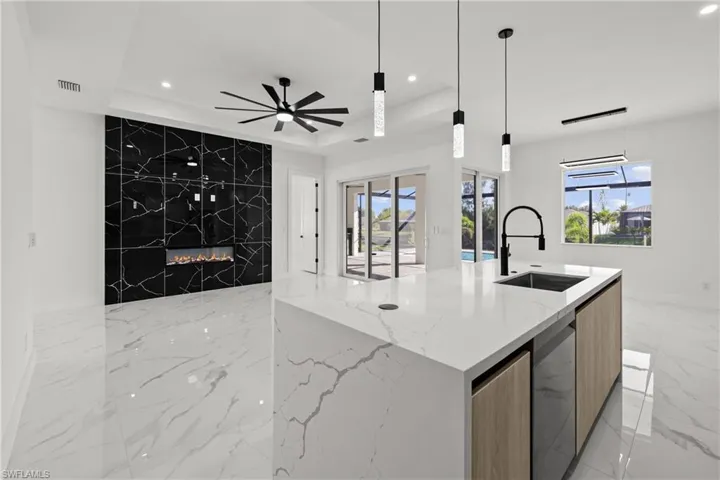 Kitchen featuring a sink, modern cabinets, light marble finish floors, a raised ceiling, and recessed lighting