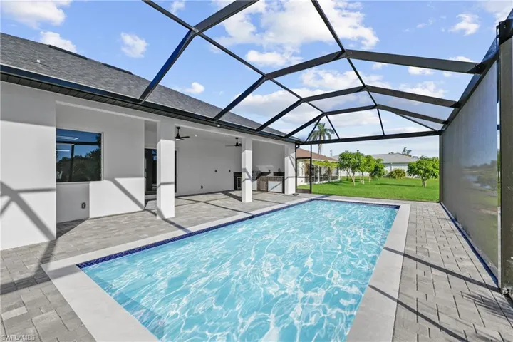 Outdoor pool featuring a patio area, ceiling fan, a lawn, and glass enclosure