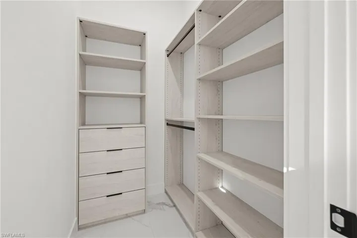 Spacious closet featuring light marble finish flooring