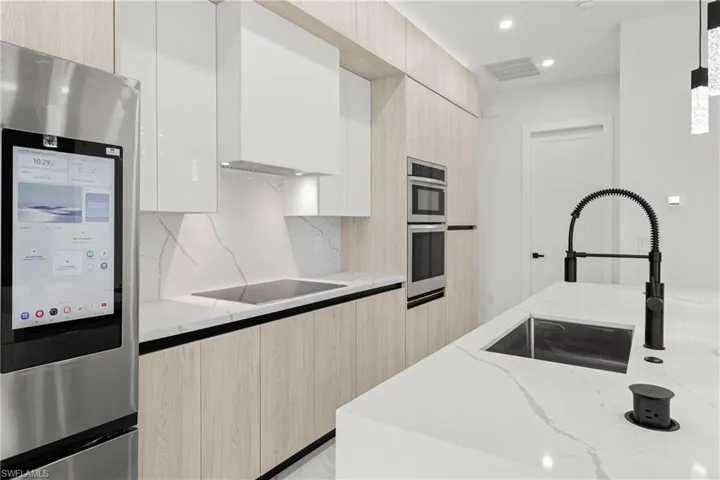Kitchen with modern cabinets, appliances with stainless steel finishes, light stone counters, and recessed lighting