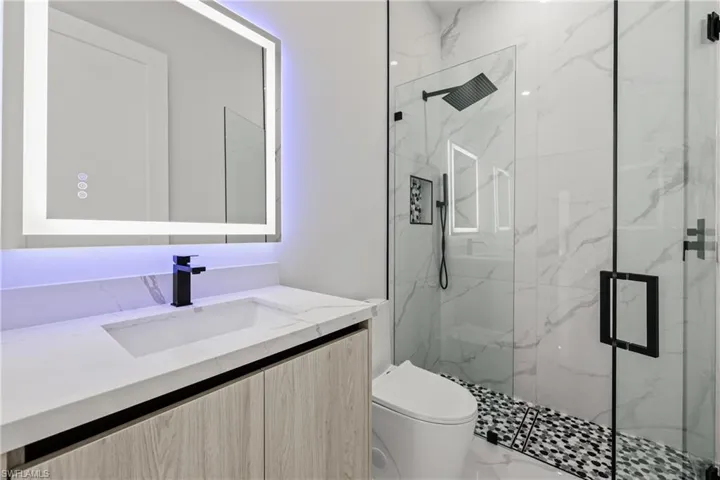 Bathroom featuring a marble finish shower, toilet, and vanity