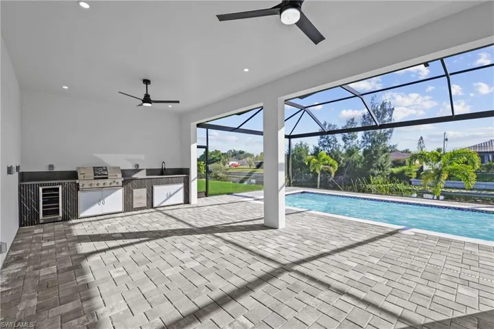 Swimming pool featuring exterior kitchen, a ceiling fan, a grill, and a patio