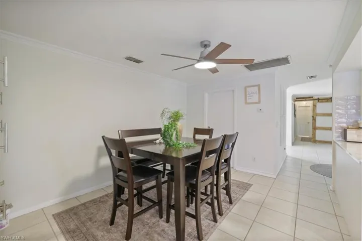 Informal Dining area with ornamental molding, light tile patterned flooring, and ceiling fan