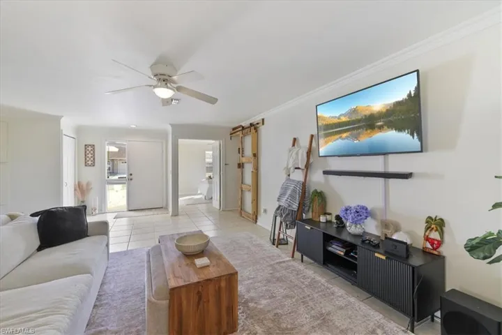 Living room, ceiling fan, ornamental molding, and light tile patterned floors