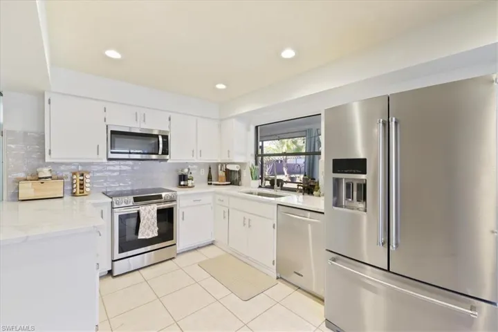 Kitchen with appliances with stainless steel finishes, white cabinets, light stone countertops, recessed lighting, and light tile patterned floors