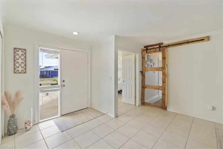 Foyer entrance with crown molding, and light tile patterned flooring