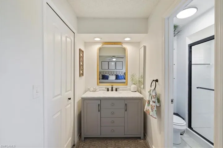 Ensuite bathroom featuring vanity, a shower stall, and a textured ceiling