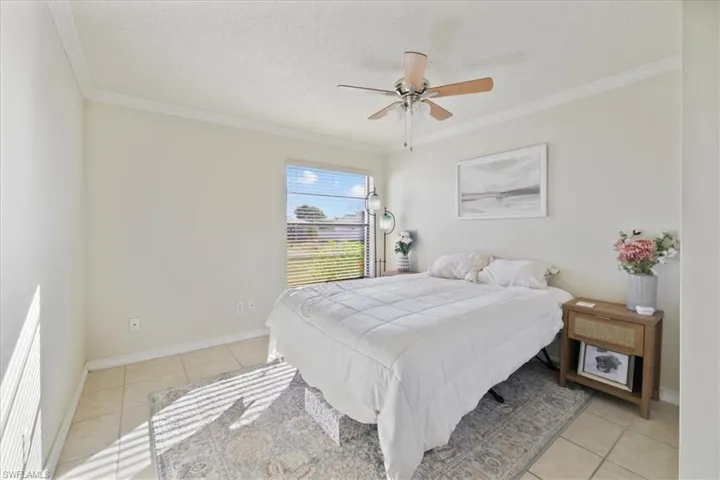 2nd Bedroom with ornamental molding, a textured ceiling, light tile patterned floors, and a ceiling fan