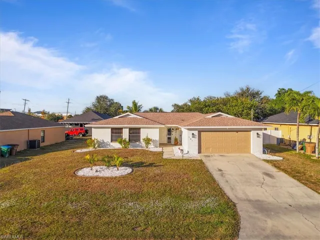Ranch-style house with a front yard, concrete driveway, and an attached garage