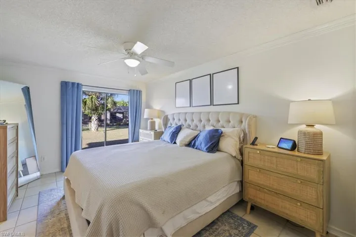 Bedroom with light tile patterned floors, a textured ceiling, ornamental molding, access to outside, and a ceiling fan