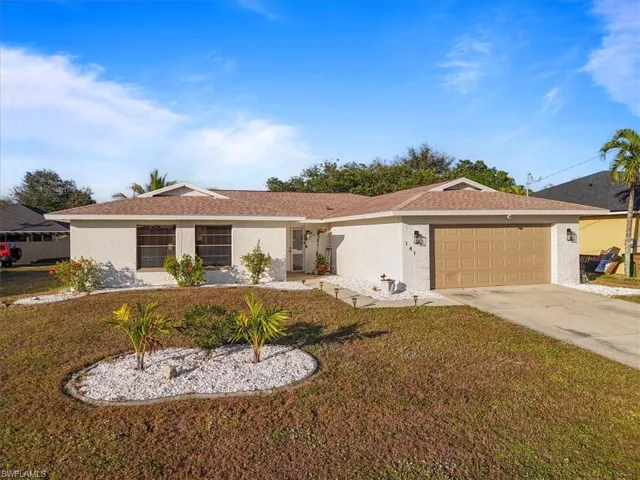Ranch-style house with a front yard, concrete driveway, and an attached garage