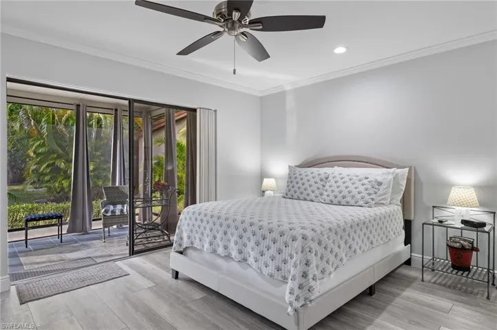 Bedroom with light hardwood / wood-style floors, ornamental molding, access to exterior, and ceiling fan