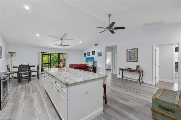 Kitchen featuring lofted ceiling, white cabinets, a center island, ceiling fan, and light hardwood / wood-style floors