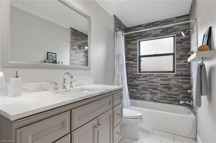 Full bathroom with shower / tub combo, tile patterned floors, toilet, and vanity