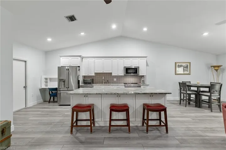 Kitchen featuring a kitchen island with sink, lofted ceiling, light hardwood / wood-style flooring, and appliances with stainless steel finishes