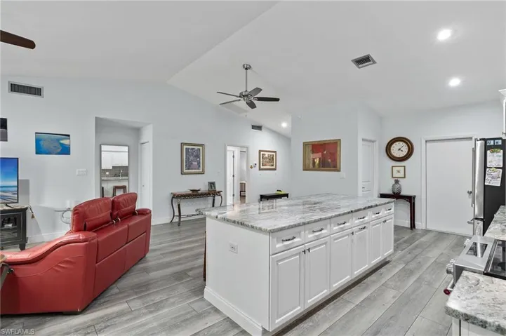 Kitchen with light hardwood / wood-style floors, white cabinets, ceiling fan, and vaulted ceiling