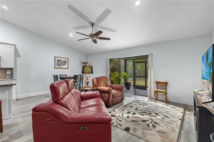 Living room with light wood-type flooring, ceiling fan, and lofted ceiling