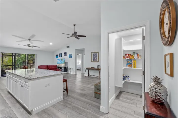 Kitchen with white cabinetry, vaulted ceiling, light hardwood / wood-style flooring, and ceiling fan