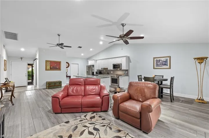 Living room with sink, ceiling fan, lofted ceiling, and light hardwood / wood-style floors