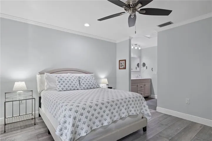 Bedroom with crown molding, ceiling fan, connected bathroom, and hardwood / wood-style floors