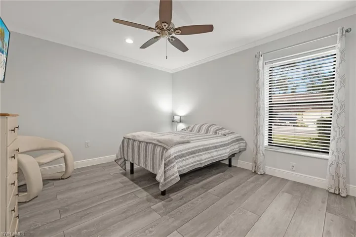 Bedroom with ornamental molding, ceiling fan, and light wood-type flooring