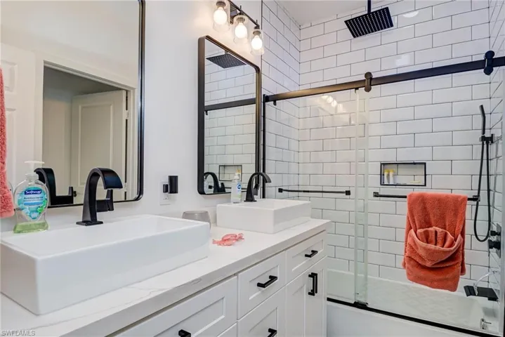 Bathroom with double vanity, a shower with shower door, and a sink