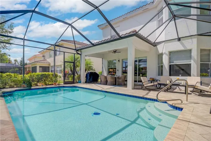 Outdoor pool with a ceiling fan, a patio, glass enclosure, and an outdoor hangout area