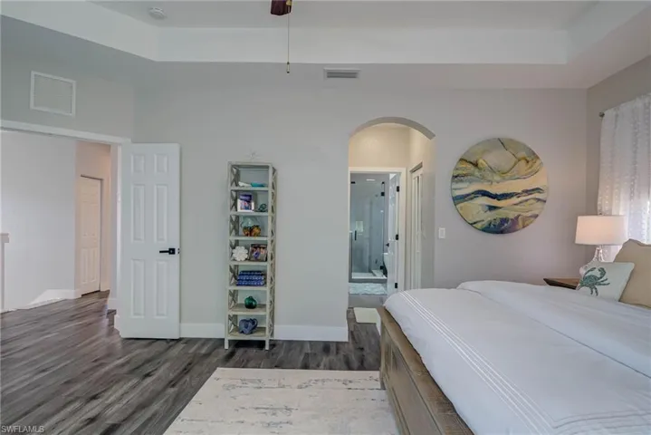 Bedroom featuring visible vents, ensuite bath, dark wood finished floors, and arched walkways