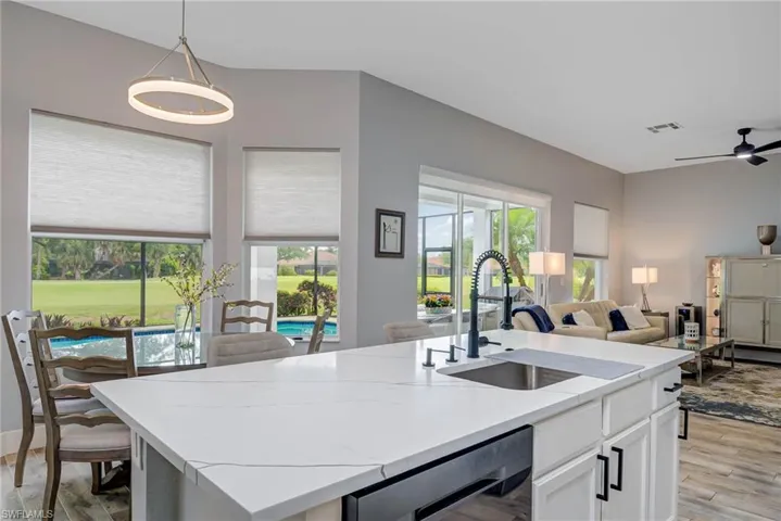 Kitchen featuring visible vents, open floor plan, white cabinets, and a sink