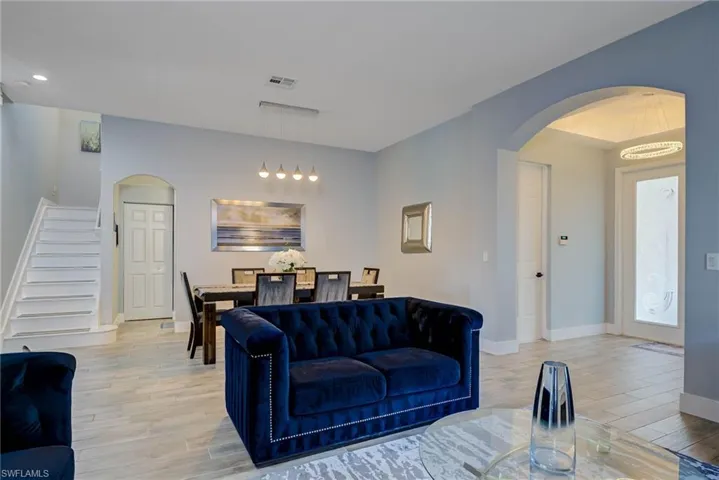 Living area with visible vents, light wood-type flooring, baseboards, and arched walkways